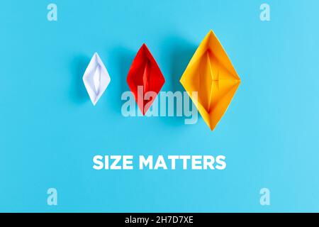 Business corporate or company size decision concept. Three paper boats with different size and colors on blue background with the text size matters. Stock Photo