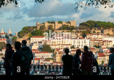 Silhouettes of tourists and visitors admiring the view of Lisbon from St. Peter's observation point (Miradouro de Sao Pedro de Alcantara) in the Bairr Stock Photo