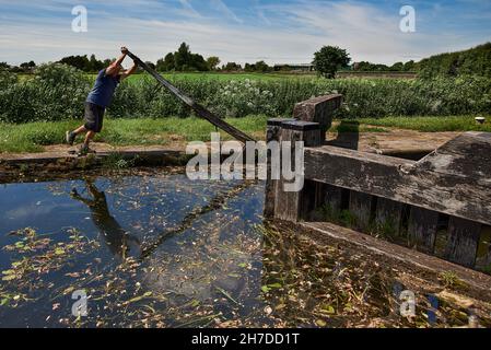 one man working an old traditional lock on the remote, rural Rufford branch of the Leeds and Liverpool canal in Lancashire, north west England Stock Photo