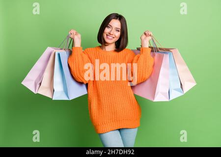 Portrait of attractive cheerful girl holding new things consumerism market isolated over bright green color background Stock Photo