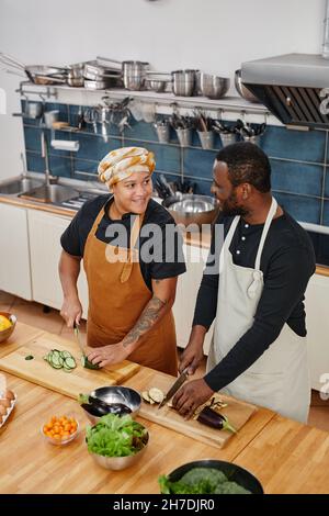 Vertical high angle portrait of two people enjoying cooking vegetables in kitchen interior Stock Photo