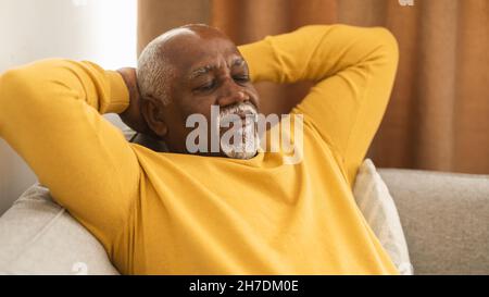 Senior Black Man Sleeping Holding Hands Behind Head At Home Stock Photo