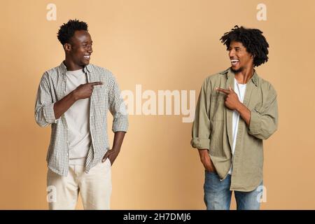 Its Him. Two Cheerful Black Male Friends Pointing At Each Other Stock Photo