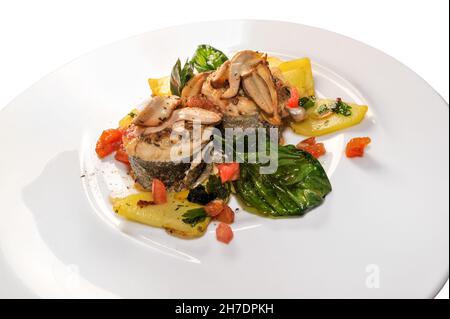 Baked eel with porcini mushrooms (Boletus edulis), potatoes, tomatoes and basil leaves in white dish isolated on binco, close up Stock Photo