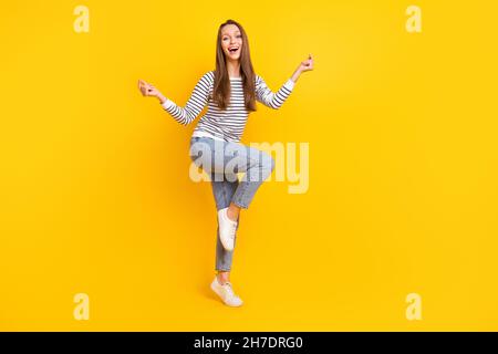 Full size photo of lovely brunette millennial lady dance wear jumper jeans sneakers isolated on yellow color background Stock Photo