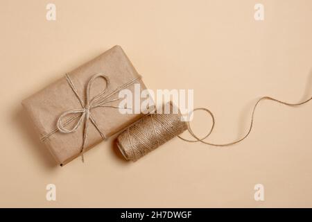 Packing order with recycling material. kraft paper gift on beige background. eco box gift with twine bow. Stock Photo