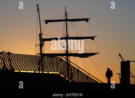 Hamburg, Germany. 22nd Nov, 2021. A man walks along the Elbe promenade as the sun slowly sets. Credit: Marcus Brandt/dpa/Alamy Live News Stock Photo