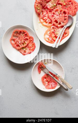 Pink tomato salad with chopped spring onions, olive oil, dried oregano and sea salt flakes Stock Photo