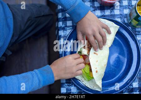A child's hands rolling a filled burrito Stock Photo