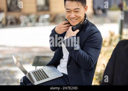 Asian business man working on laptop outdoors Stock Photo