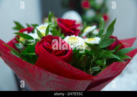 fresh red roses in a bouquet as background . red roses bouquet . White chamomile rose . Red roses on a red satin background . Stock Photo