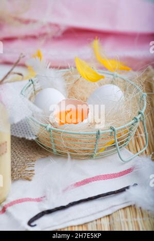Fresh eggs with feathers in a wire basket Stock Photo