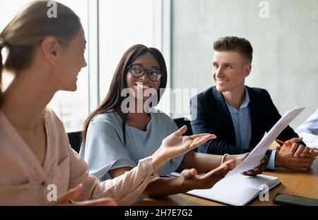 Happy Multiethnic Coworkers Discussing Marketing Plan While Having Meeting In Modern Office Stock Photo