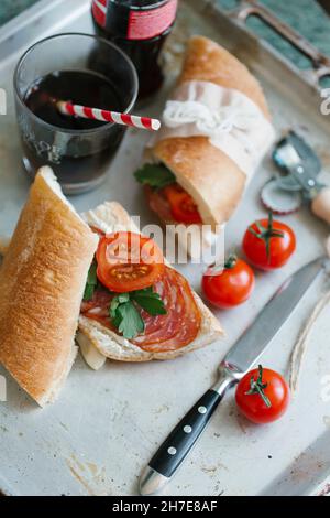 Sandwiches with cream cheese, salami, tomatoes and parsley, with a glass of cola Stock Photo