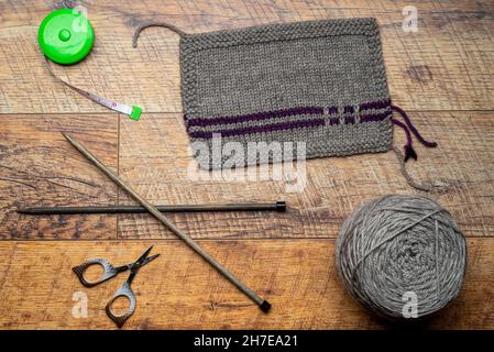 Beige yarn knitted swatch, wooden background testing a wool with knitted piece. Stock Photo