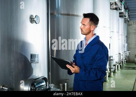 Young man in coat taking notes on wine factory Stock Photo