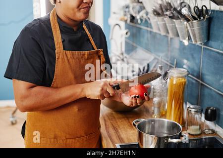 Cropped portrait of unrecognizable woman cutting vegetables while working in professional kitchen, copy space Stock Photo