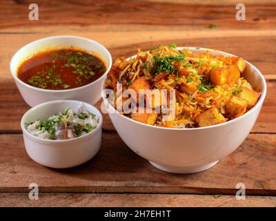 Hyderabadi Veg Paneer Dum Biryani with mixed veggies like Paneer, Potato, Carrots, Peas cooked along with spiced rice and served with onion raita and Stock Photo