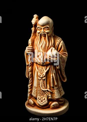 Macro of a small figure of the god Shu (one of the Three Star Elders). Shu is the god of longevity, health and immortality - with a peach in his hand Stock Photo