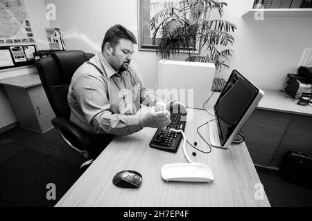 JOHANNESBURG, SOUTH AFRICA - Aug 09, 2021: A grayscale of an angry working male frustrated for the laptop that is not working Stock Photo