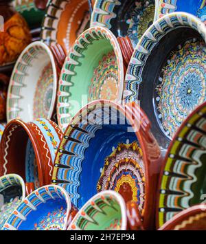 Painted Bulgarian ceramic vessels with traditional motifs, plates, bowls, goblets. Handmade from brown clay. Baked glaze at high temperature Stock Photo