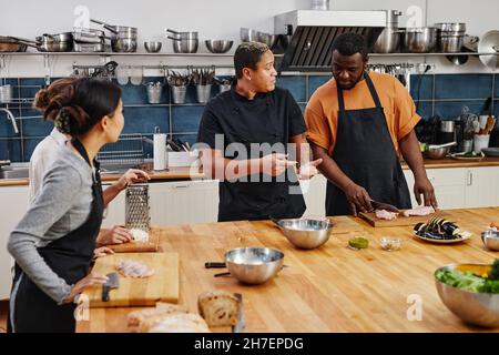 Portrait of diverse team of people cooking together in kitchen interior Stock Photo