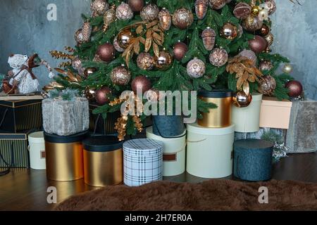 Christmas presents near tree with colorful balls. Stacked gift boxes for christmas. Stock Photo