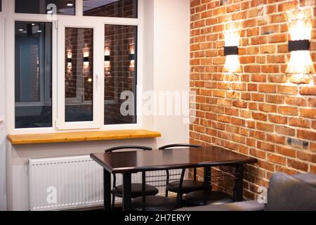 Living room interior in loft style. Sofa and dining table on a brick wall background with lamps. Stock Photo
