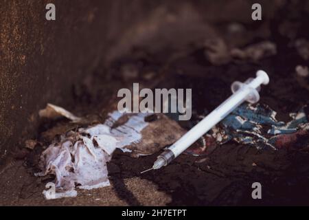 Discarded used hypodermic needle in gutter Stock Photo