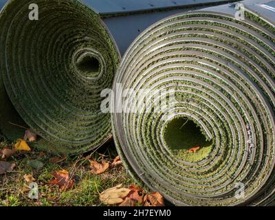 Used artificial turf in rolls after covering removal when the sport season ended. Rolled up fake grass, close up Stock Photo