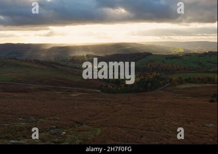 Looking out from Stanage Edge in the Peak District as the sun sets over the valley beneath. Stock Photo