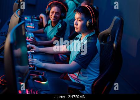 Young gamers playing online video game in cyber club Stock Photo