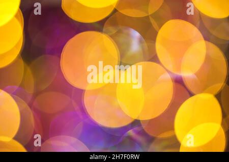 Yellow and purple glitter and abstract festive elegant background with blurred bokeh lights. Defocused holiday lighting. Stock Photo