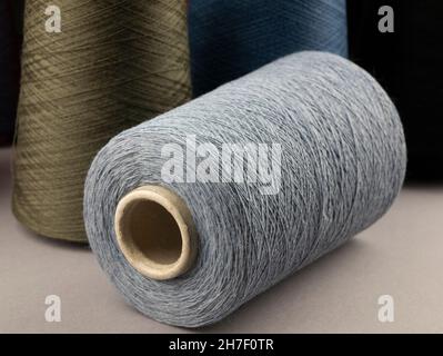Cones of neutral tones threads. Bobbins of cotton, woolen or synthetic yarn for textile manufacturing or handmade products, close up Stock Photo