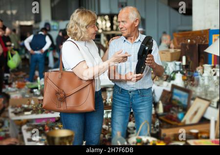 Mature man and his wife are visiting market of old things Stock Photo