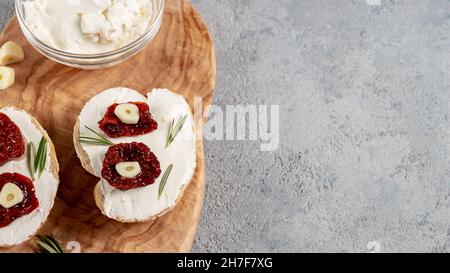 Homemade sandwiches with cream cheese and sun-dried tomatoes on a wooden board of olive - delicious healthy breakfast, italian cuisine, copy space, fl Stock Photo