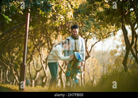 asian family with one child enjoying outdoor activity in city park Stock Photo
