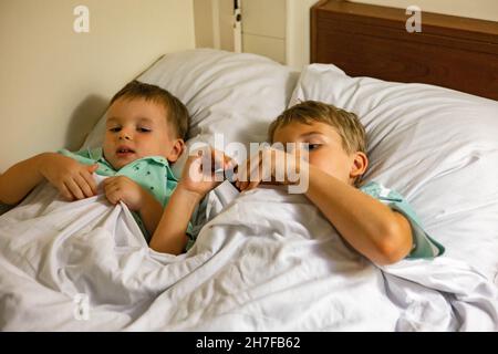 Two little brother sleeping on bed at luxury comfortable railway carriage enjoying travel by train Stock Photo