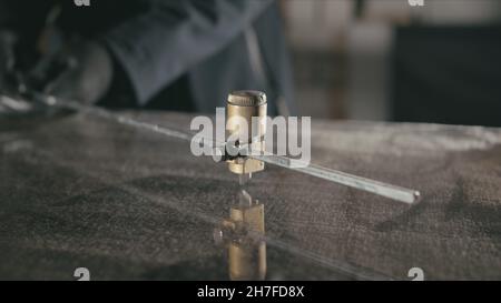 Forge. Smithy. Glass cutting and processing for fireplace doors. Circular glass cutter. Worker cut glass with glass cutting diamond. Polish an angle g Stock Photo