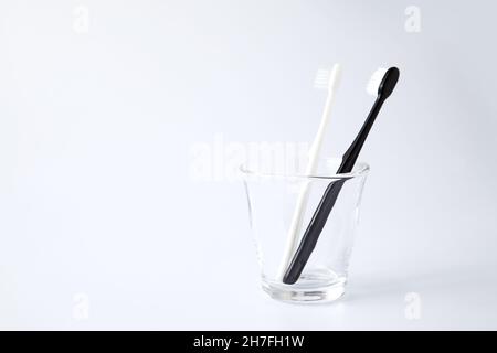white black toothbrushes in glass toiletries isolated on white background Stock Photo