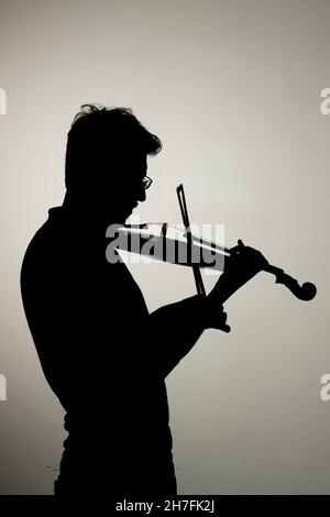 Silhouette of man playing violin on grey background Stock Photo