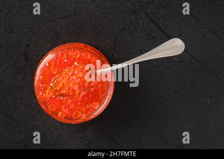 Overhead view of open jar with red caviar and a spoon in it Stock Photo