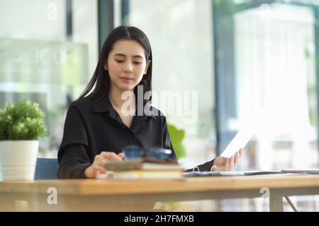 Attractive young businesswoman working with her assignment at the co working space of coffee shop. Stock Photo