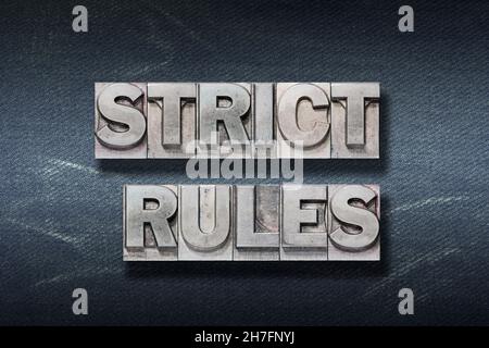 strict rules phrase made from metallic letterpress on dark jeans background Stock Photo