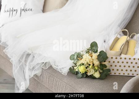 Beautiful bouquet, wedding dress and shoes on sofa Stock Photo