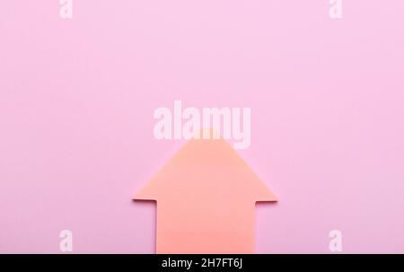 Sticky notes in shape of arrow on pink background Stock Photo