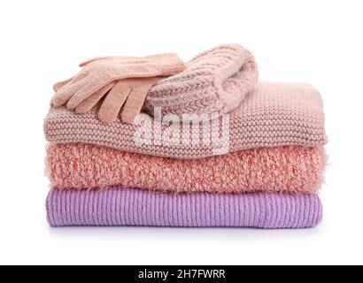 Stack of stylish sweaters, gloves and hat on white background Stock Photo