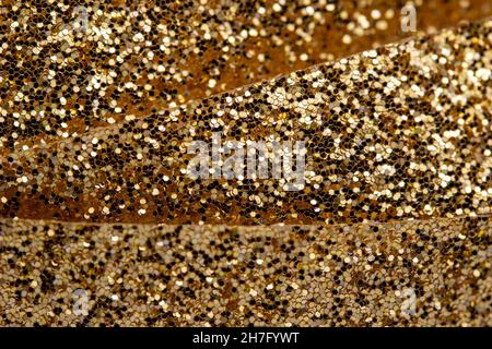 Macro abstract texture background of sparkling gold color Christmas holiday glitter ribbon with copy space. Stock Photo