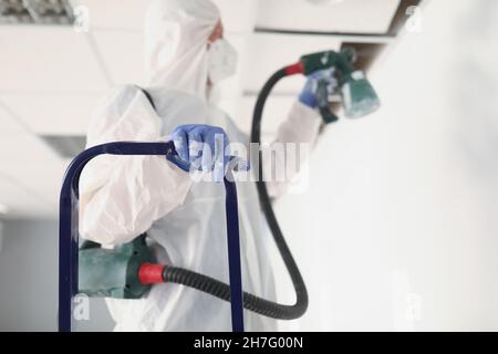 Renovation worker paint wall in uniform using spray gun Stock Photo