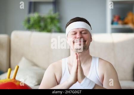 Middle aged man meditating at home put hands in namaste gesture Stock Photo